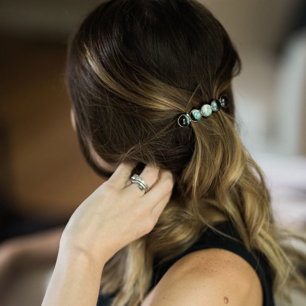 Person adjusting hair with a decorative hairpin, blurred background