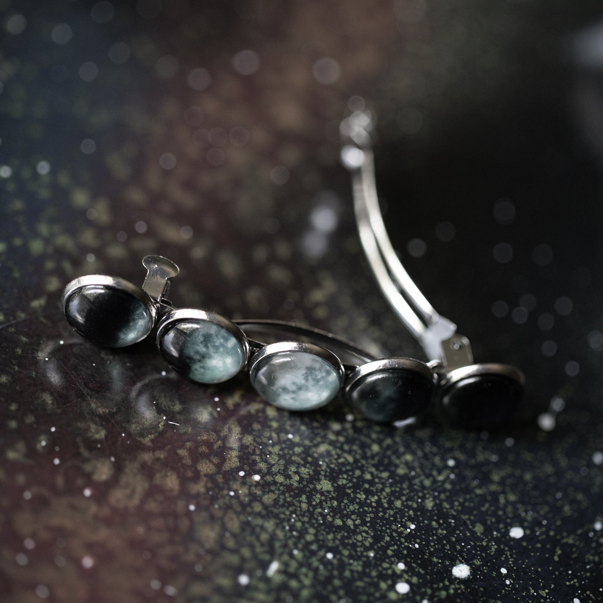 Silver hair clip with dark stones on a reflective surface